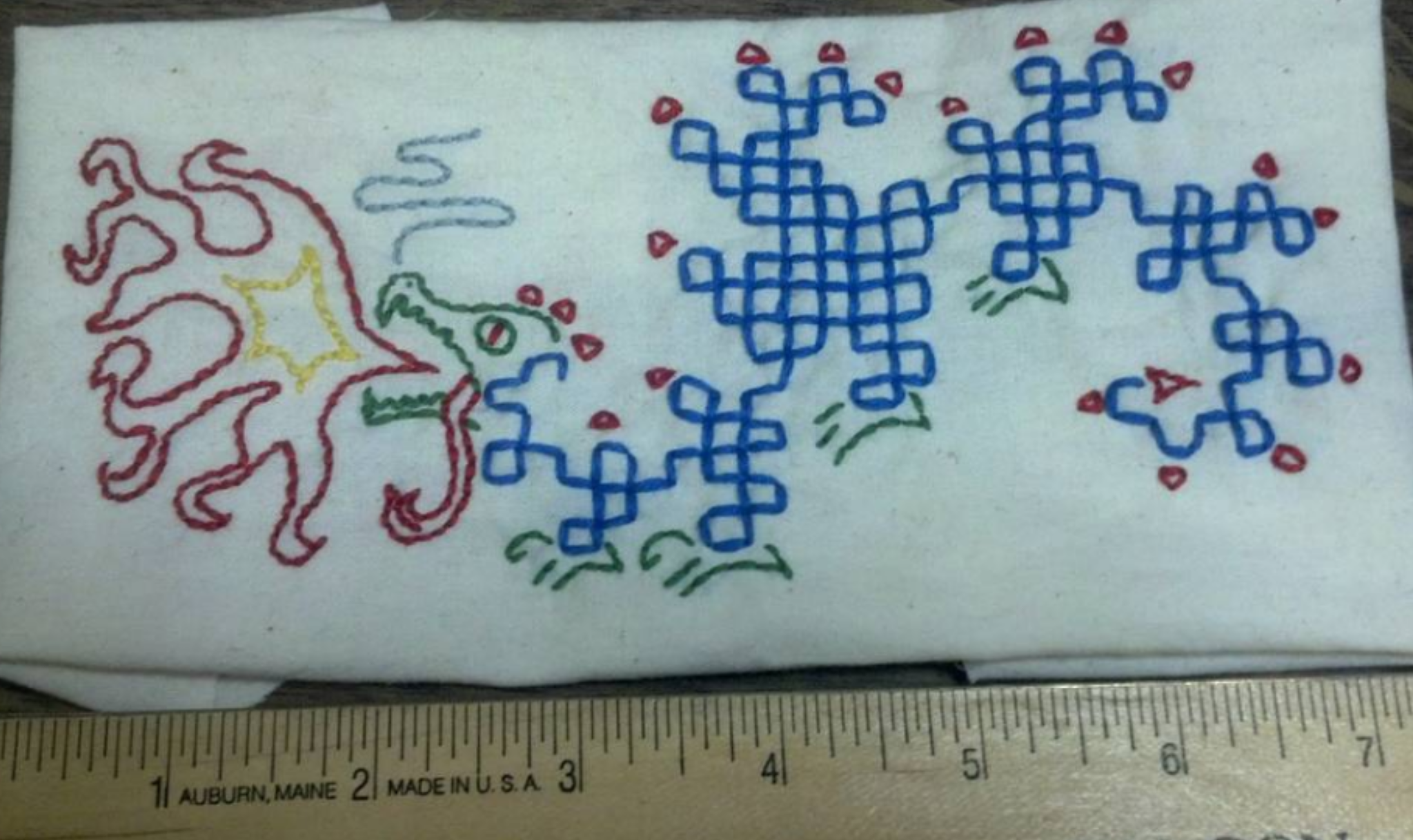 Dragon curve fractal embroidered onto a patch and embellished with a dragon head, claws, and spines.
